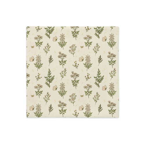 A square fabric napkin or paper napkin with a repeating botanical pattern of green leaves, beige flowers, and small butterflies on a warm cream background, shown flat against a white background.