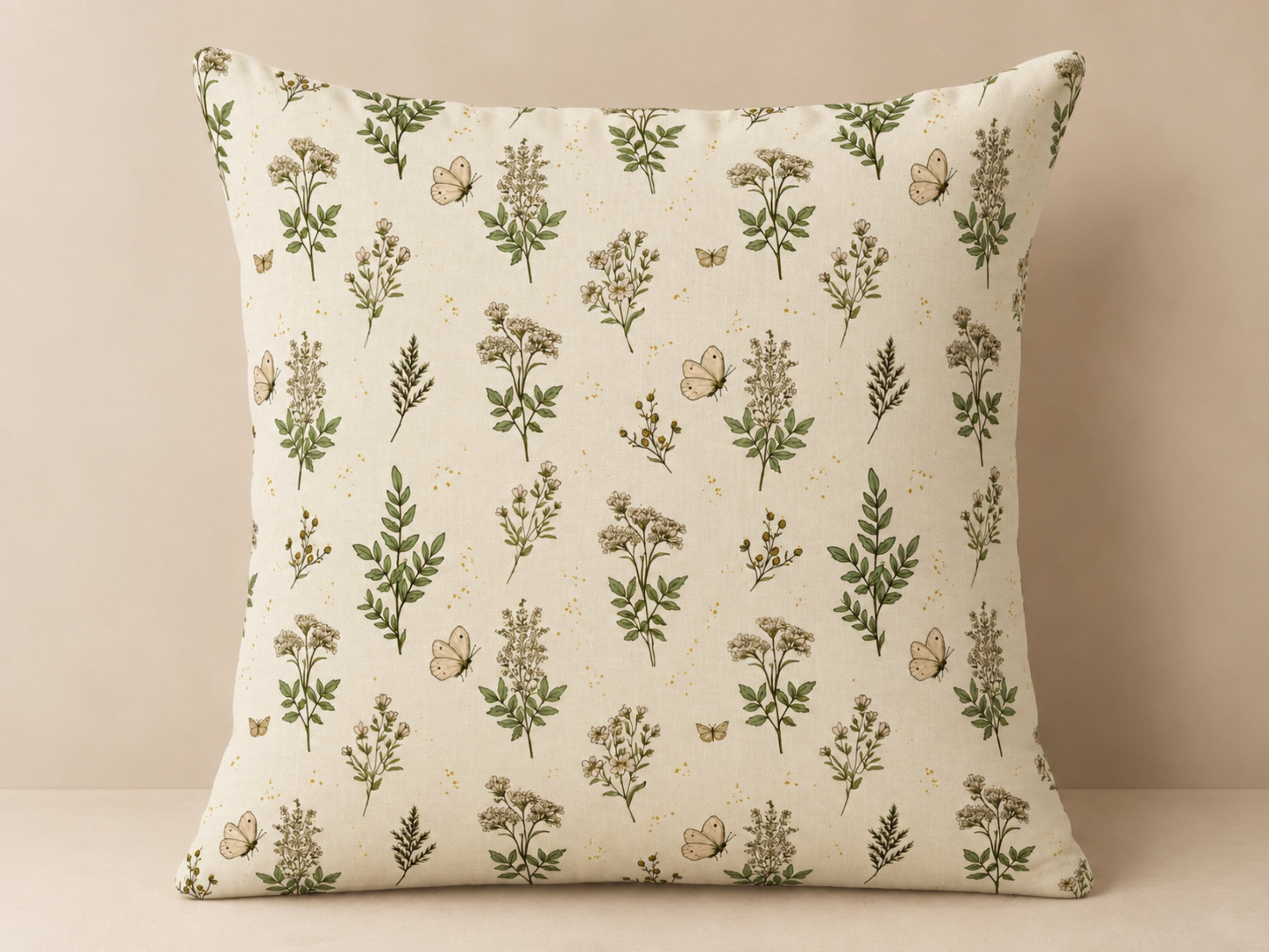 A square throw pillow with a cream-colored fabric featuring an all-over botanical pattern of green leaves, small wildflowers, and butterflies, set against a neutral beige background.