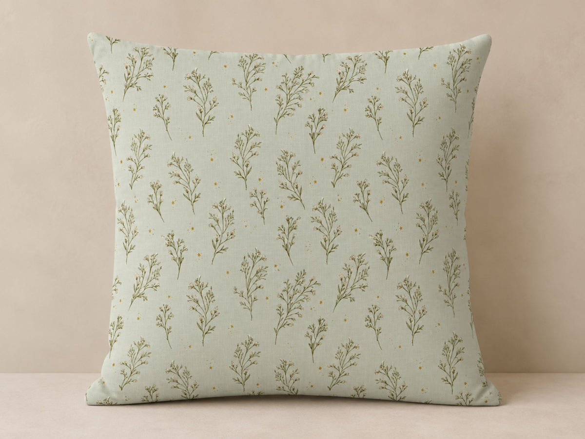A square throw pillow with a sage green and olive green botanical pattern, set against a neutral beige background.