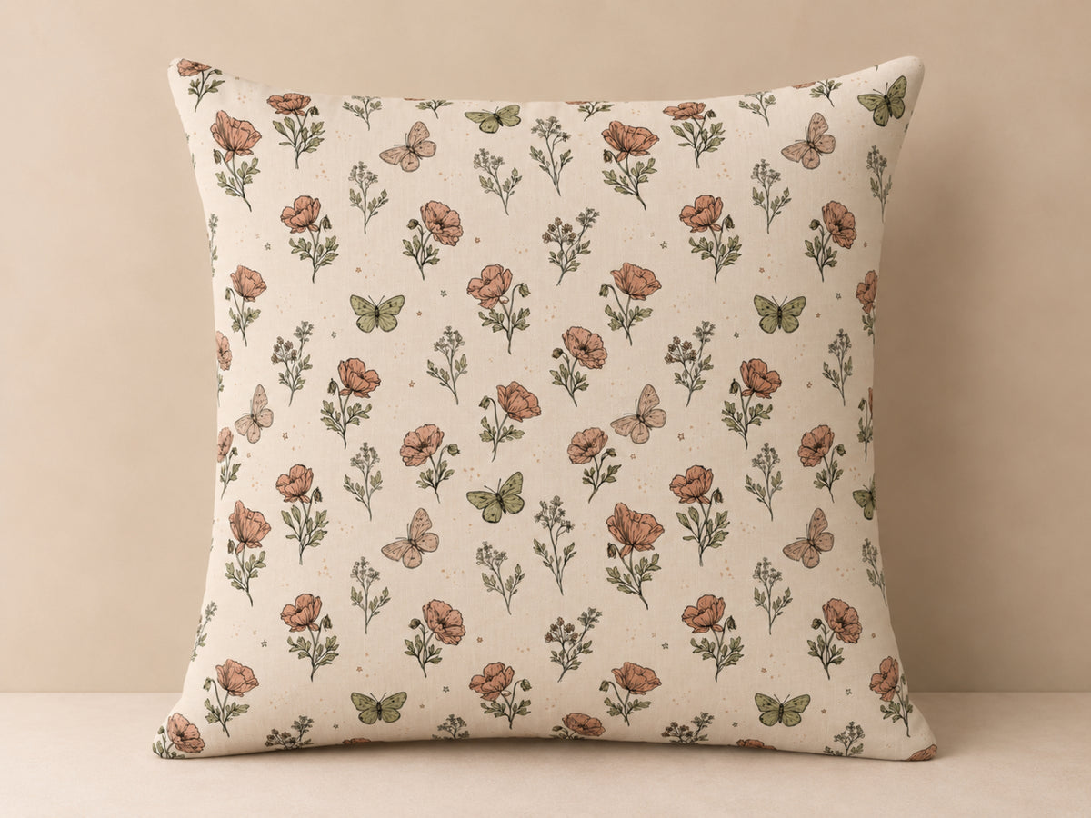 A square decorative throw pillow with a vintage-style floral and butterfly print on a cream background, set against a neutral beige backdrop.