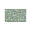 A rectangular fabric placemat or table mat featuring a repeating pattern of pale green and white moths and butterflies on a muted sage green background.